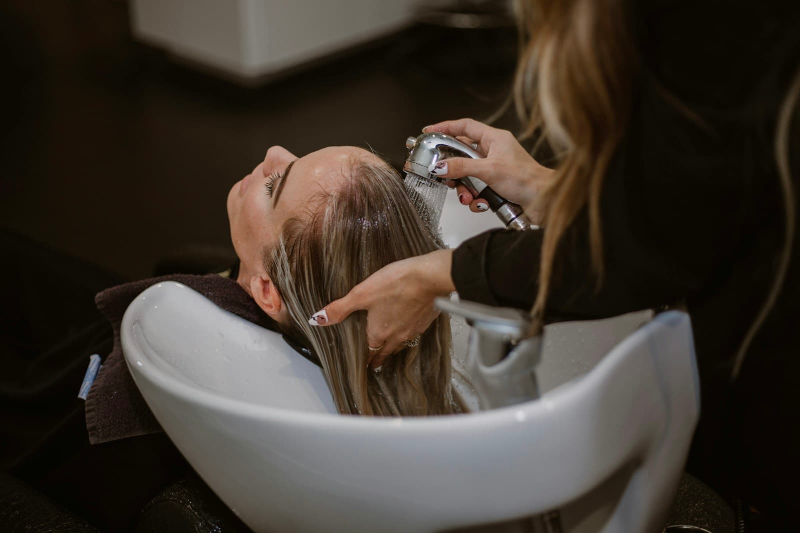 Hairdresser washing a client's hair at a salon basin